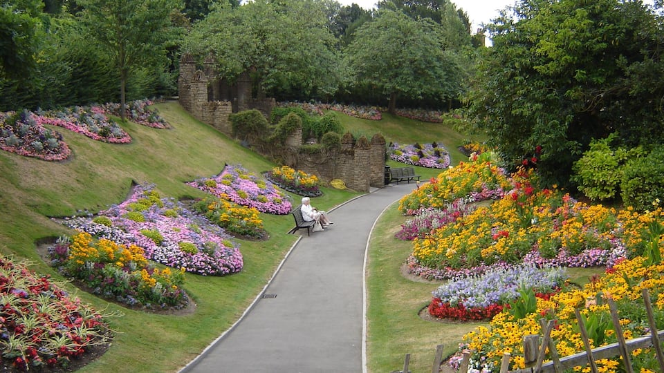 A landscaped garden with a winding path, benches, and a variety of colorful flowers.