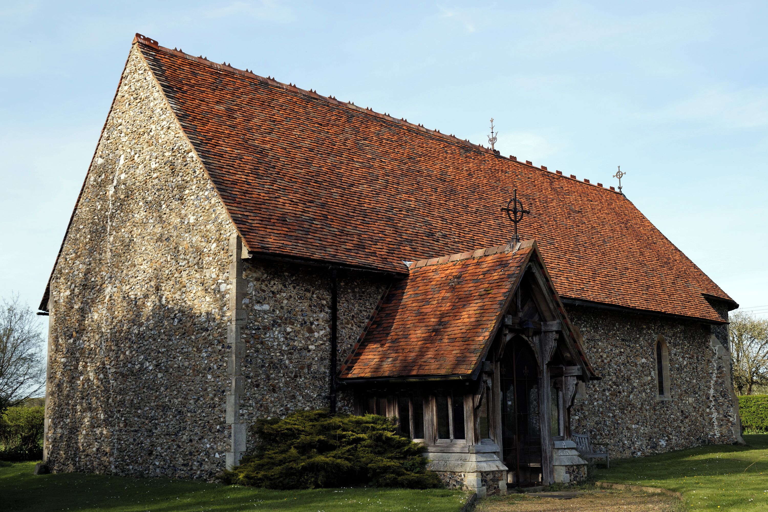A stone church with a red-tiled roof and a wooden entrance.