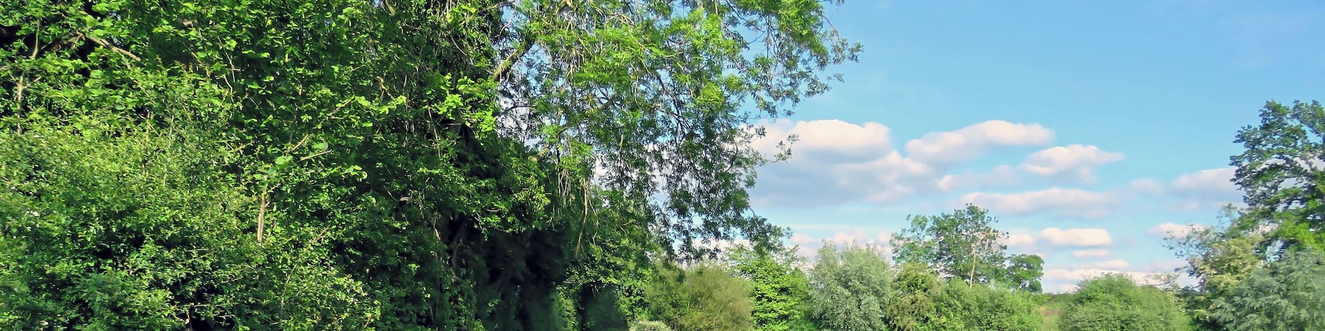 The access road running northeast away from St Mary's Parish Church, with concrete post and scaffolding barrier against an estate mid-19th-century artificial fishing lake, in the civil parish of Matching, in Essex, England. Camera: Canon PowerShot SX60 HS Software: File lens-corrected, optimized, perhaps cropped, with DxO OpticsPro 11 Elite, and likely further optimized with Adobe Photoshop CS2.