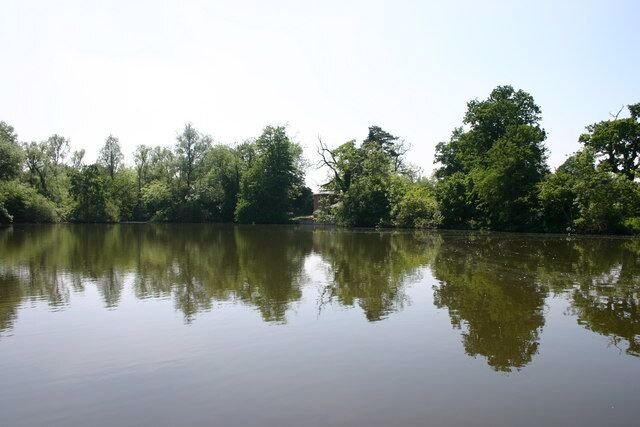 Un río tranquilo que refleja árboles y el cielo.