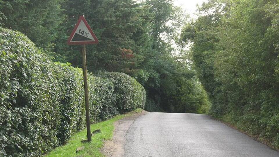 A narrow rural road with a 14% gradient sign.