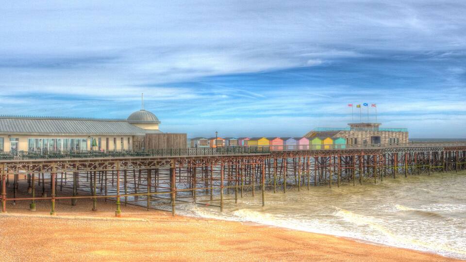 A pier with a building and colorful beach huts.