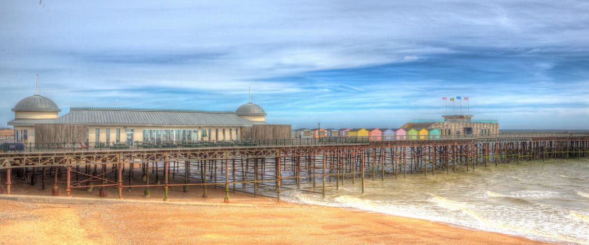 A pier with a building and colorful beach huts.