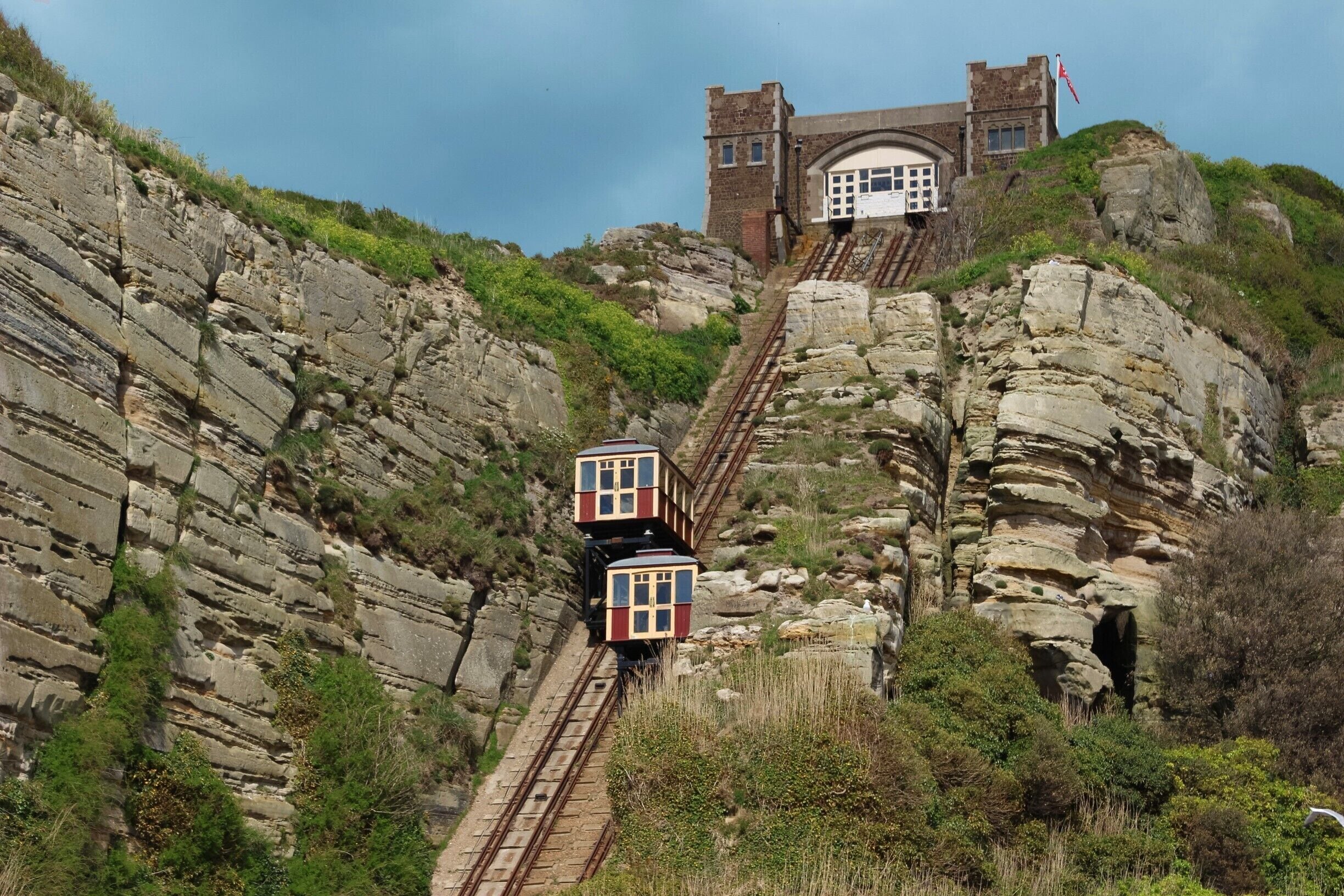 A train ascending a rocky hill with a building at the top.