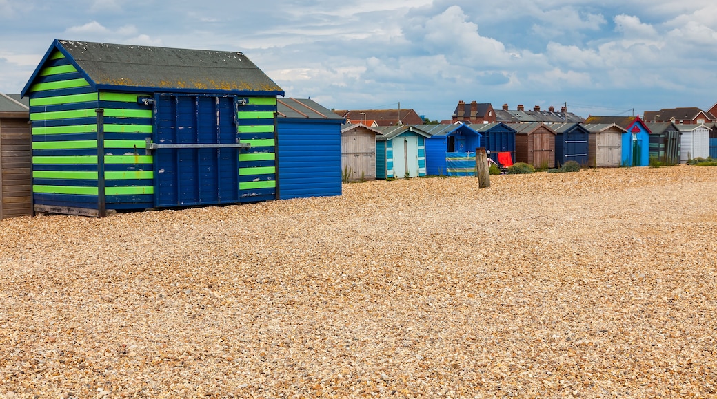 A row of colorful beach huts with a gravel beach in the foreground.