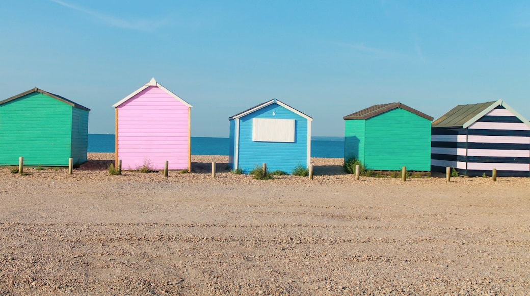 A row of colorful beach huts with a clear sky in the background.