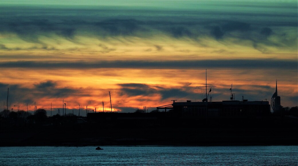 On the western tip of Hayling Island you can see the sun set behind Portsmouth's Spinnaker Tower and the small harbour on the other side of the sea channel. Large car park with walking access to the large sand beach on the corner. #perspective