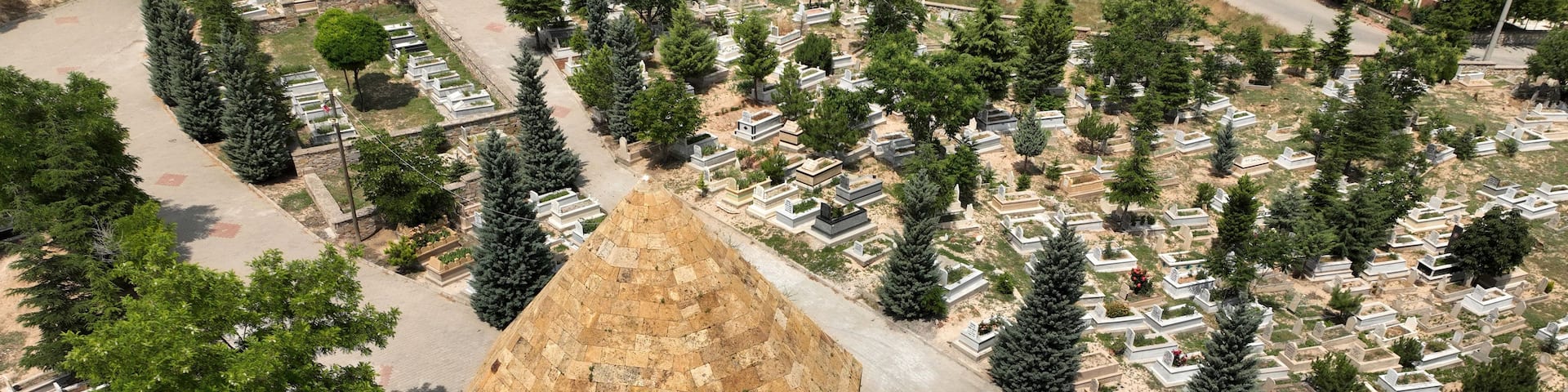 An aerial view of a cemetery with a prominent stone structure and rows of graves.