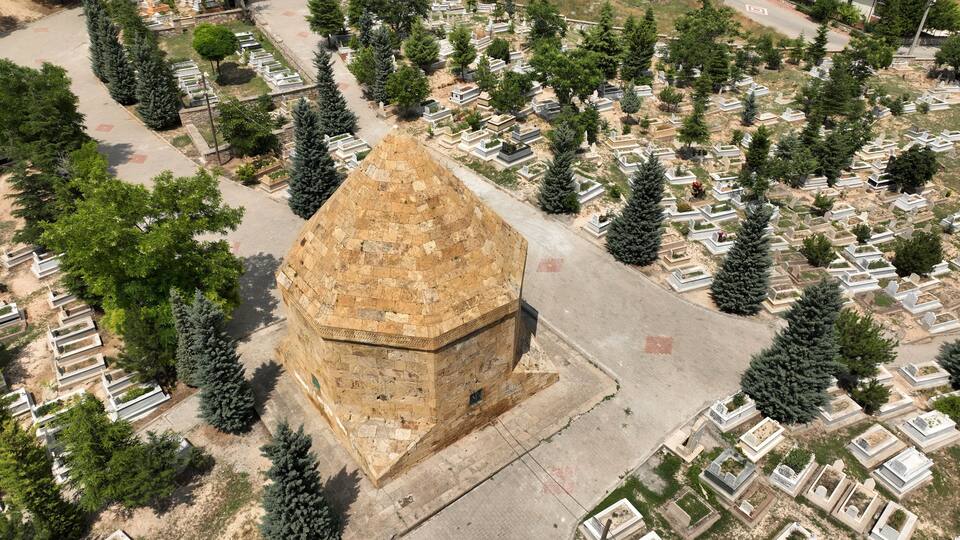An aerial view of a cemetery with a prominent stone structure and rows of graves.