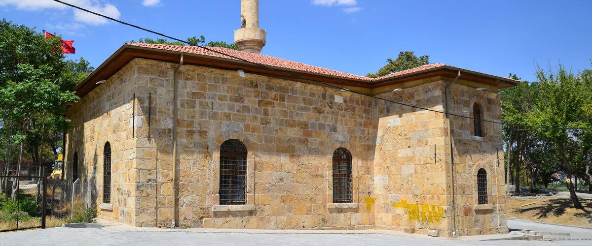 A stone building with a red-tiled roof and a minaret.