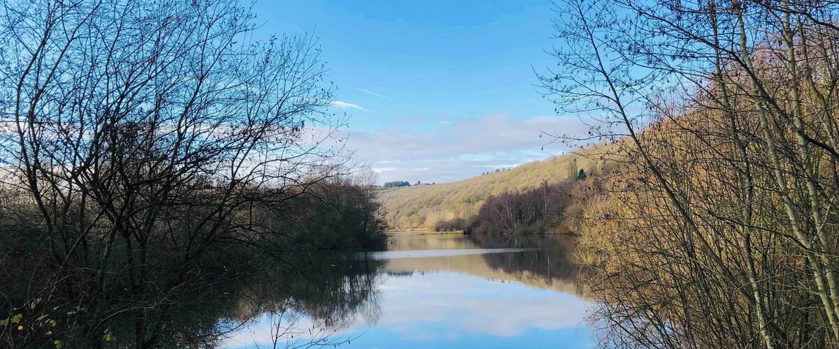 A calm lake surrounded by trees and hills.