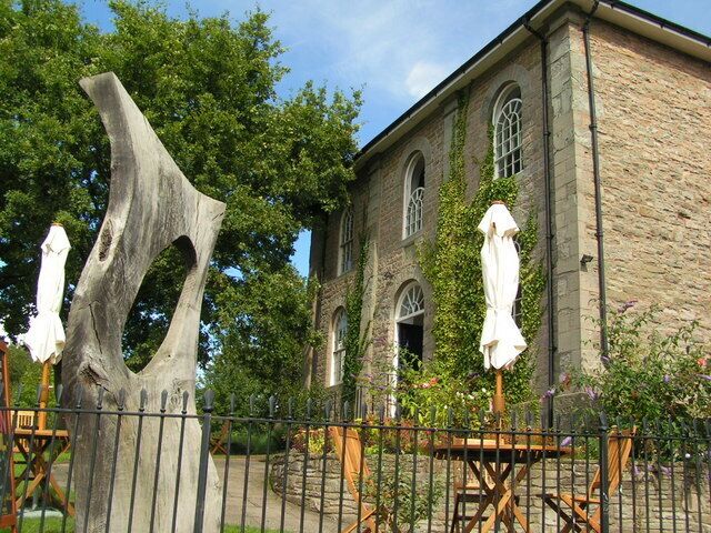 A stone building with arched windows and ivy climbing up its walls.