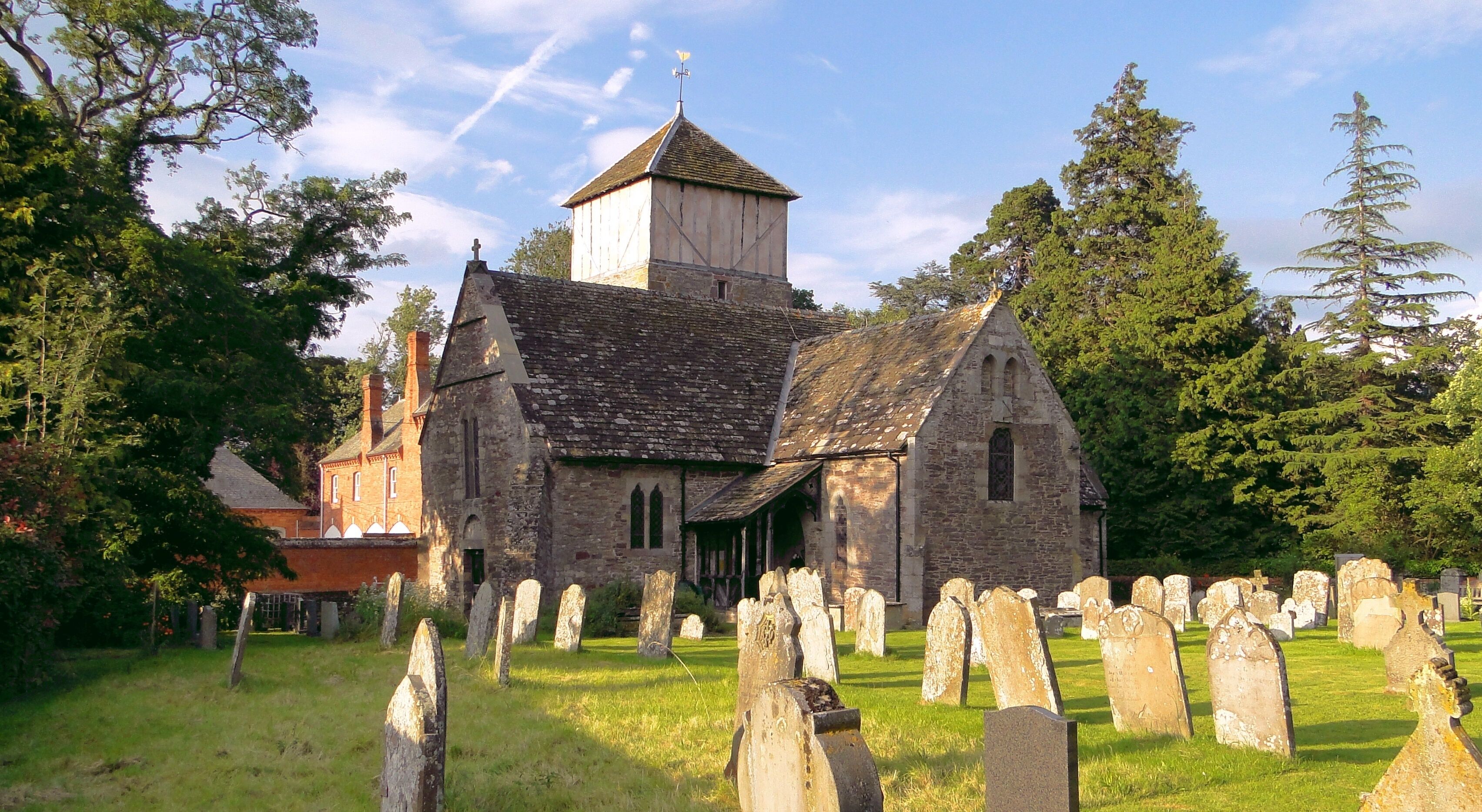 A historic church with a bell tower and a graveyard in front.