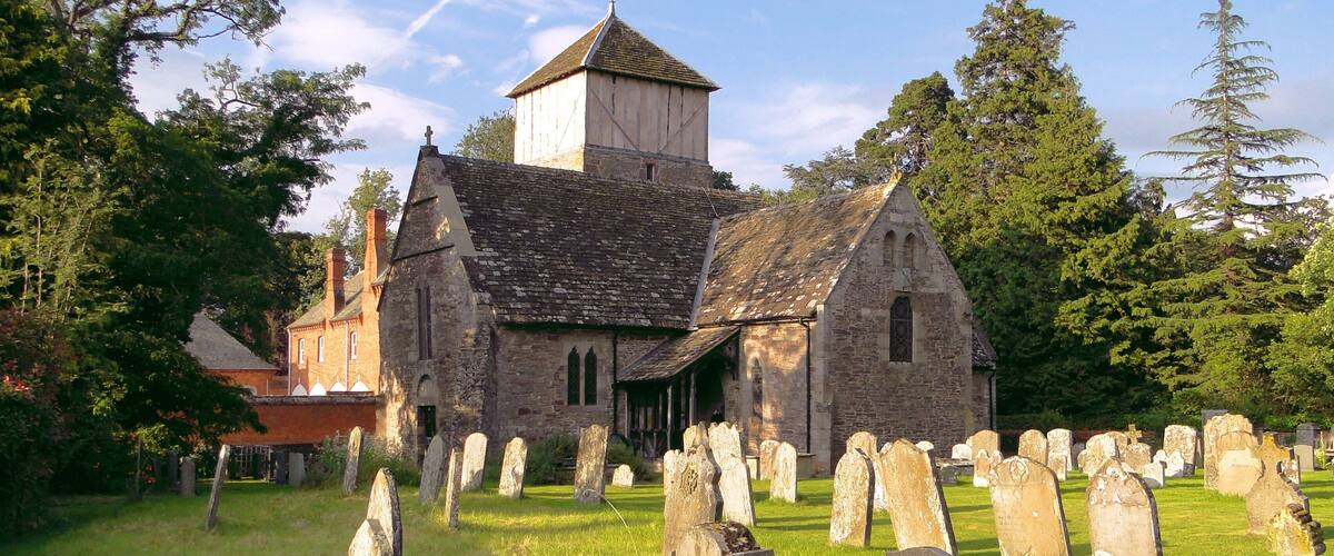 A historic church with a bell tower and a graveyard in front.
