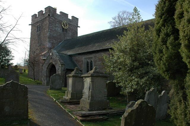 A church with a clock tower, gravestones, and a cemetery.