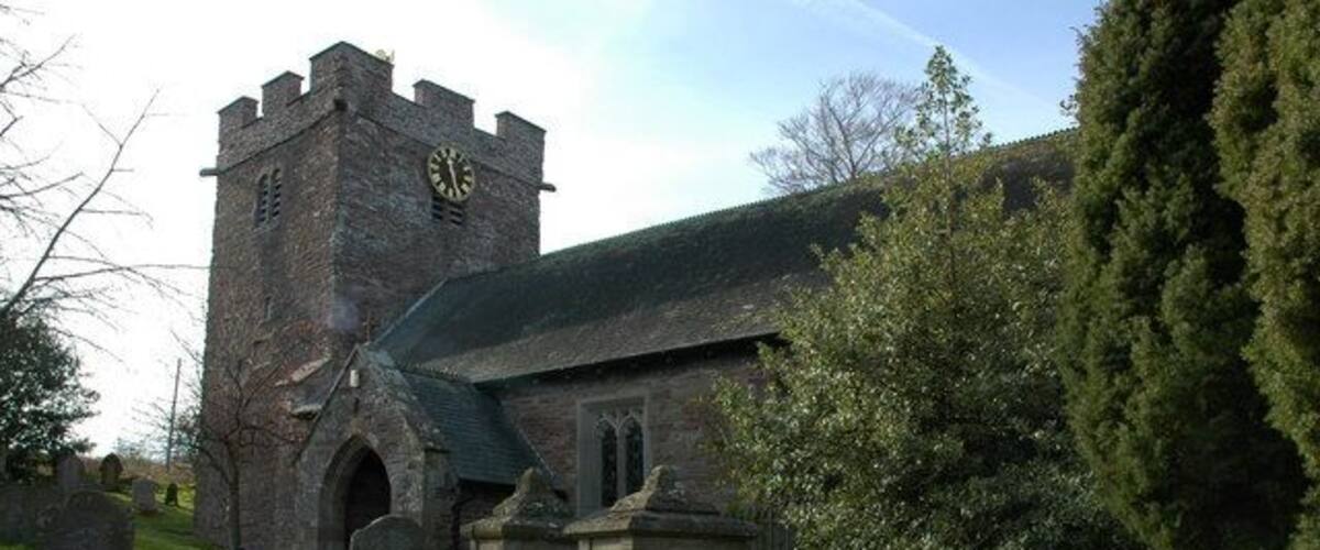 A church with a clock tower, gravestones, and a cemetery.
