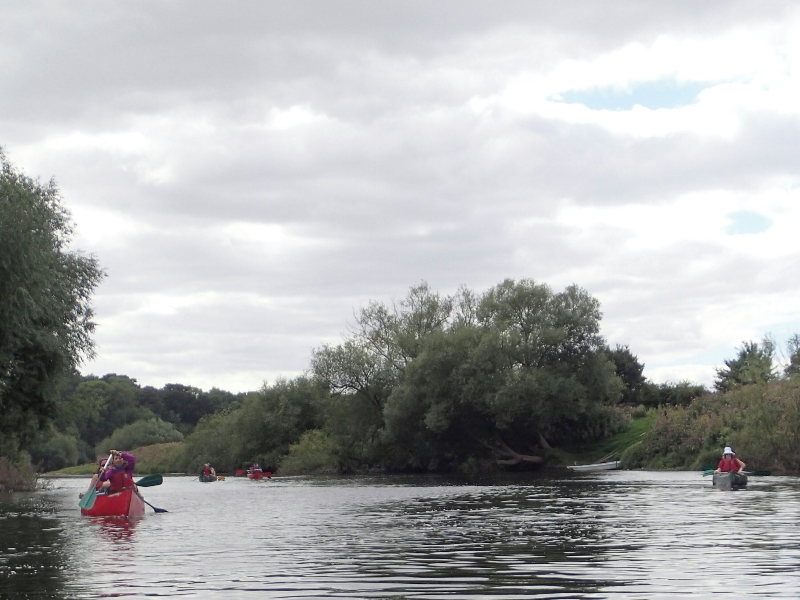 A calm river with people paddling kayaks.