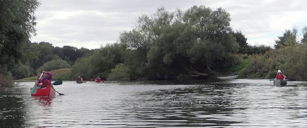 A calm river with people paddling kayaks.