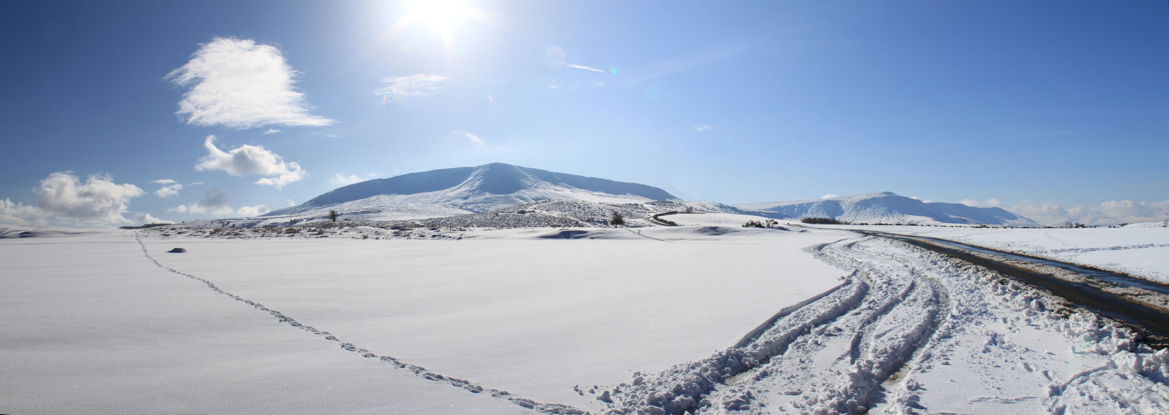 A snowy landscape with a mountain, a clear sky, and a railway track.