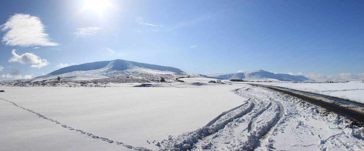 A snowy landscape with a mountain, a clear sky, and a railway track.