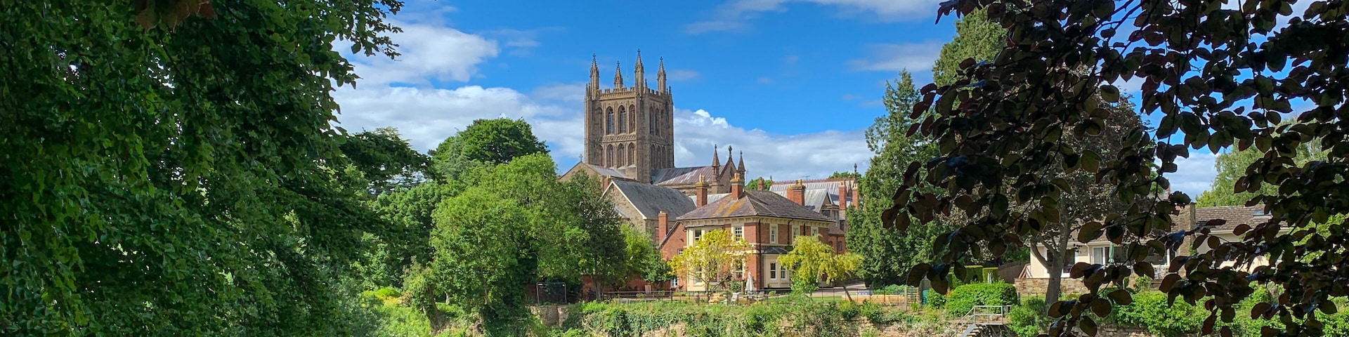 A river with a historic building and trees in the foreground.