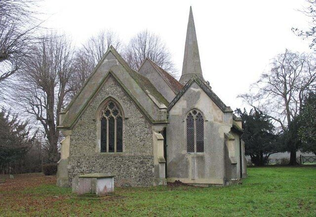 A small stone church with a pointed steeple and arched windows.