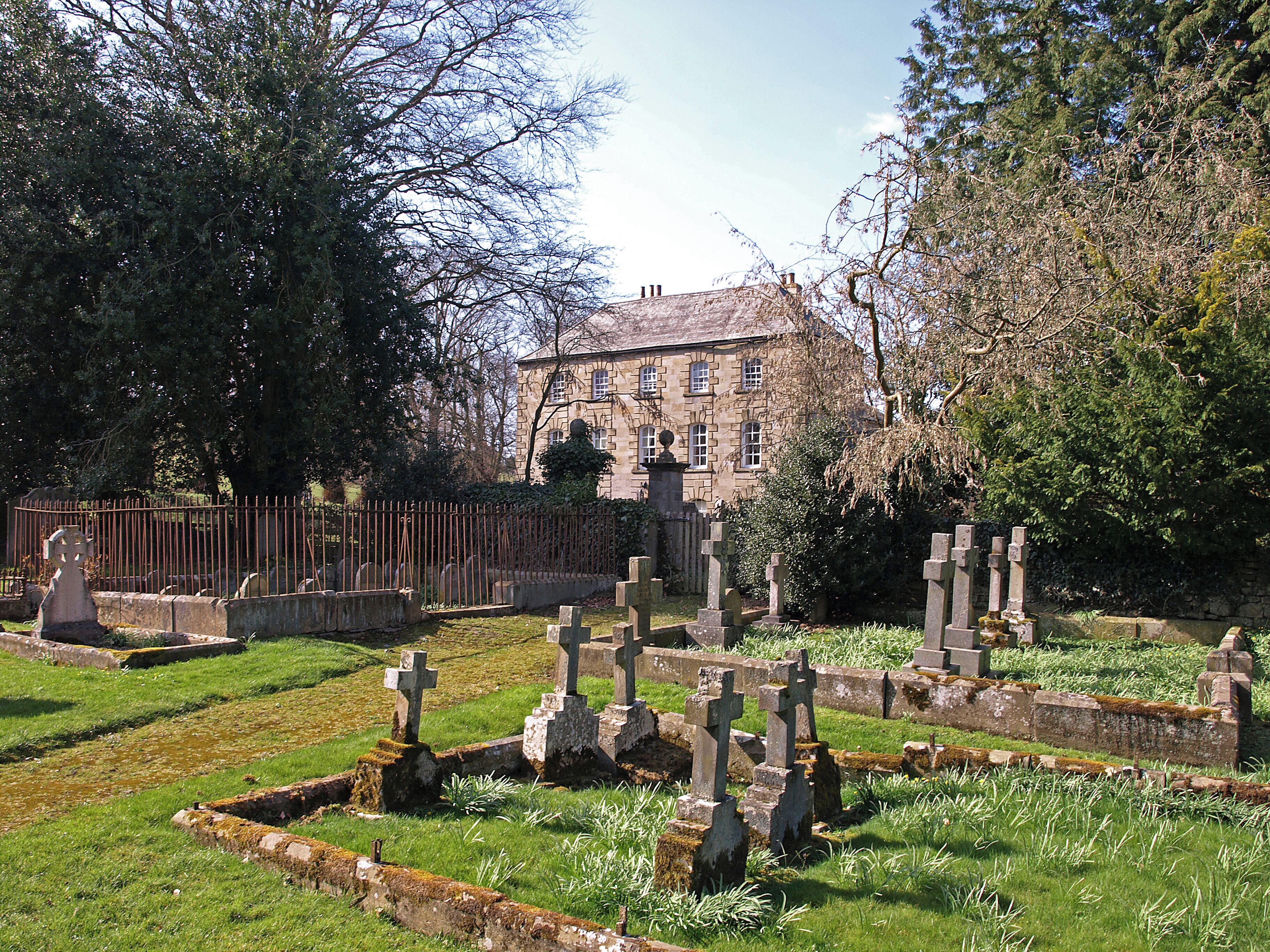 A cemetery with stone crosses and a historic building in the background.