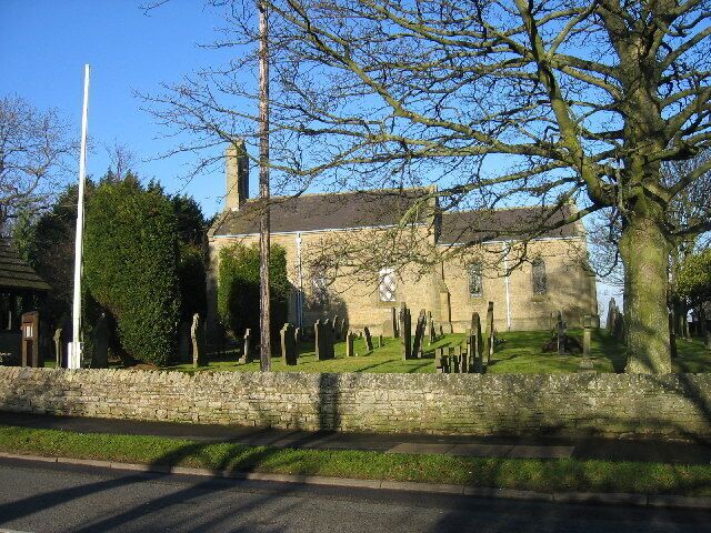 A historic building with a stone wall, a flagpole, and a cemetery.
