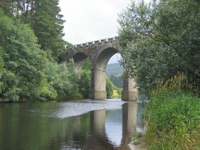 A stone bridge over a river surrounded by lush greenery.