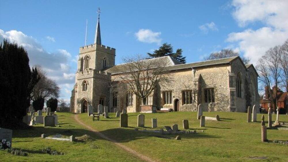 A church with a tall steeple and a graveyard in front.