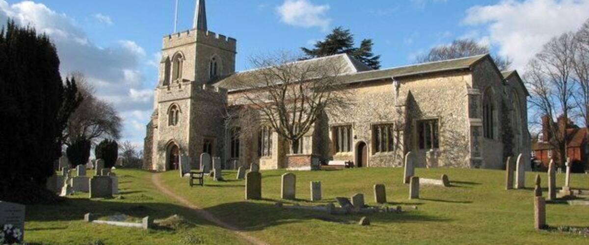 A church with a tall steeple and a graveyard in front.
