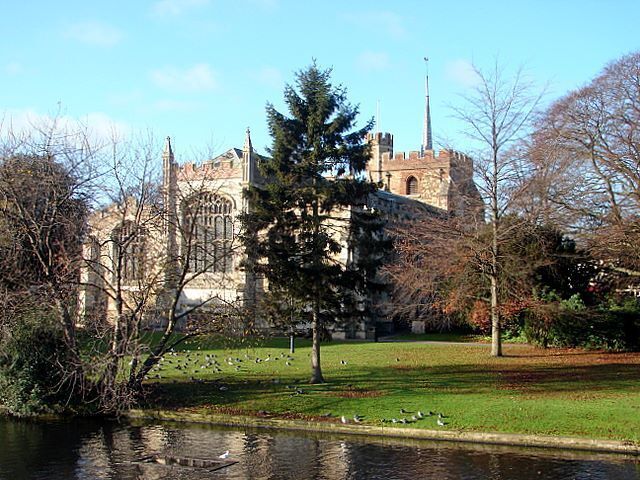 A historic building with a tower, surrounded by a grassy area and a body of water.