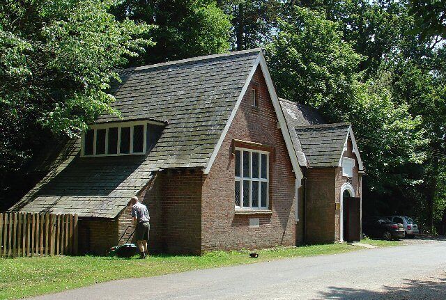 A brick building with a steep roof, a window, and a person standing nearby.