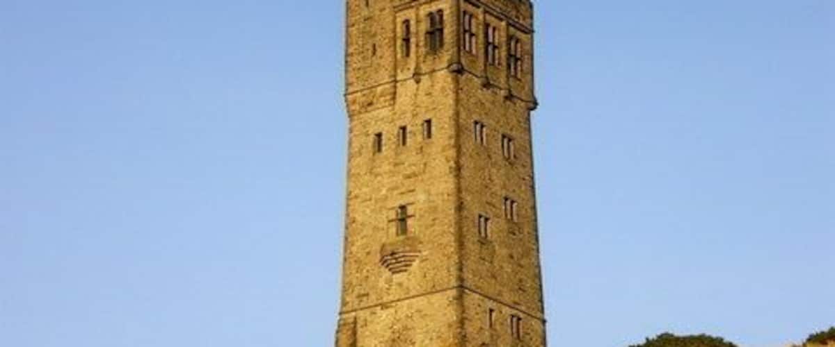 A tall, ancient stone tower on a hill with dry grass and sparse vegetation.