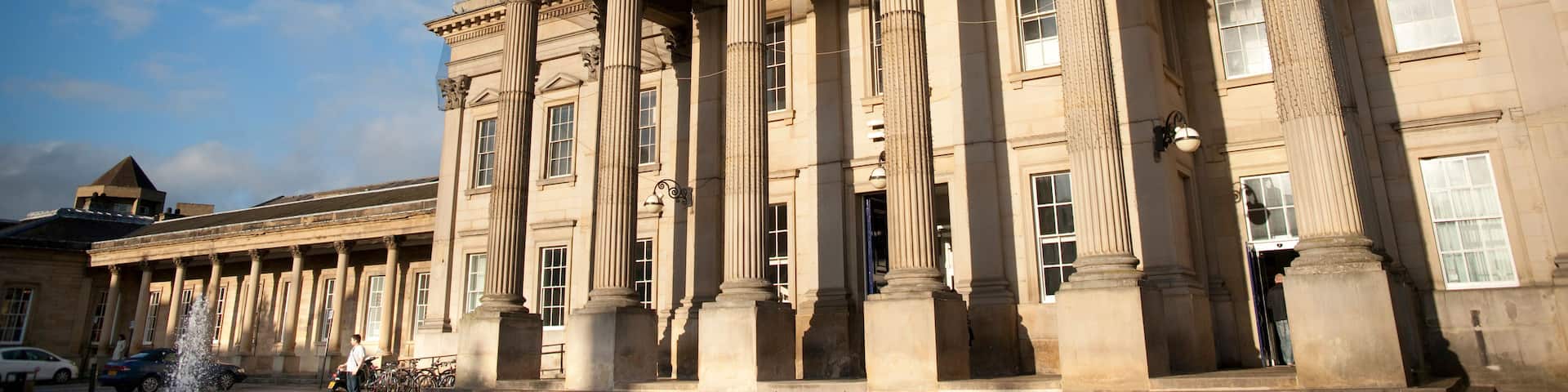 A classical building with large columns and a clock on the facade.