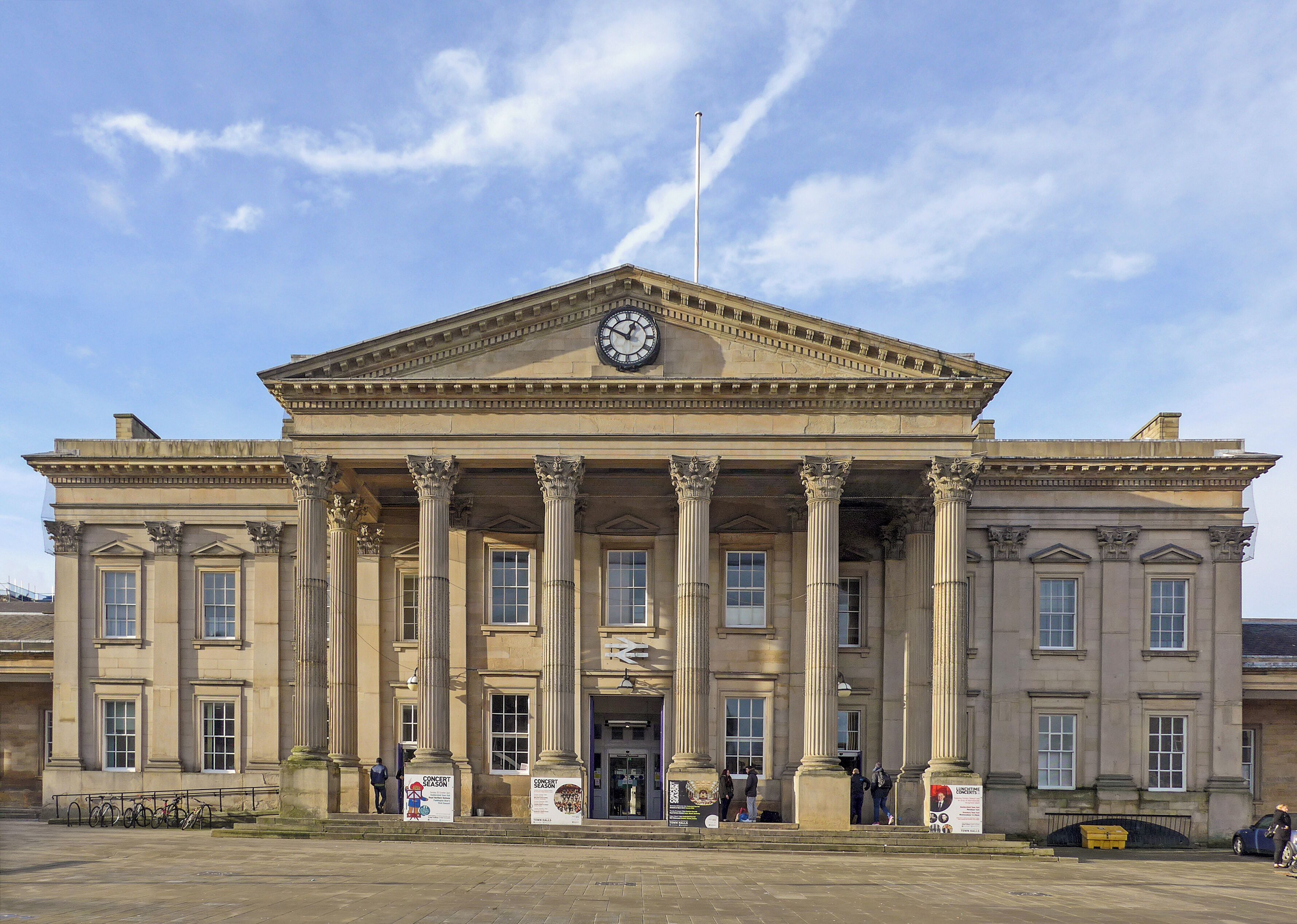 A large neoclassical building with columns, a clock, and a flagpole.