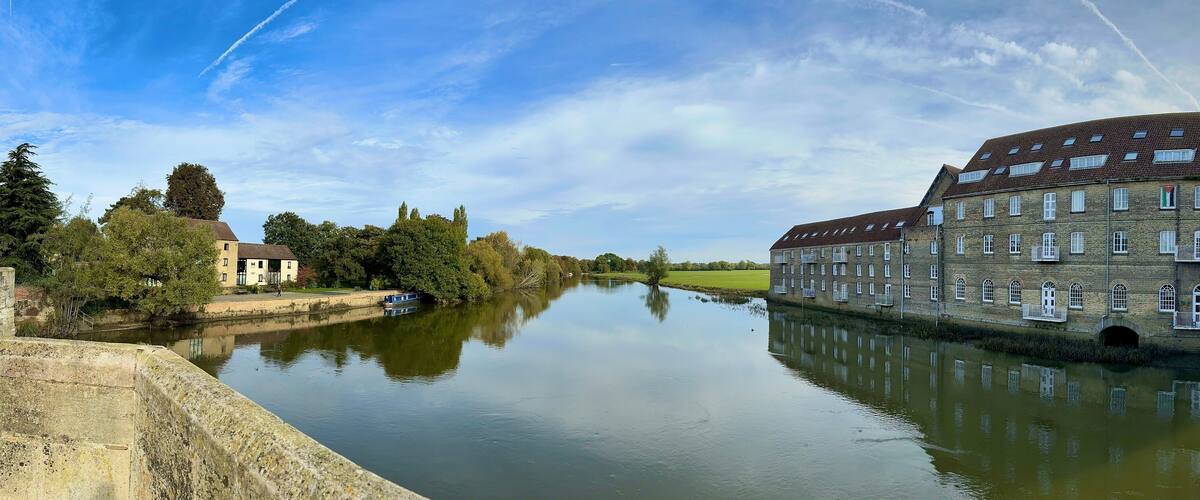 A scenic panoramic view of the historic Riverside Mill building overlooking the River Great Ouse at Huntingdon, Cambridgeshire, UK.