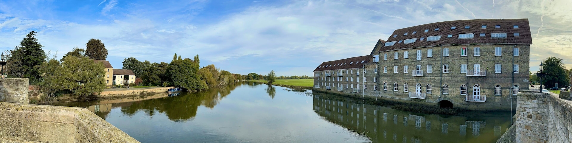 A scenic panoramic view of the historic Riverside Mill building overlooking the River Great Ouse at Huntingdon, Cambridgeshire, UK.