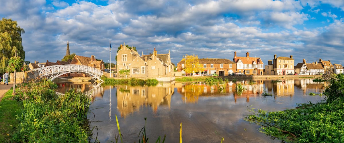 A river with a white bridge, historic buildings, and a church spire.