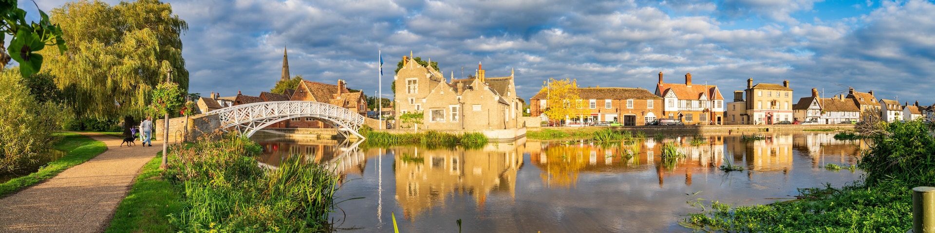 A river with a white bridge, historic buildings, and a church spire.