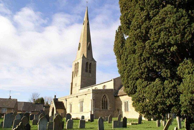 A church with a tall steeple and a graveyard in front.