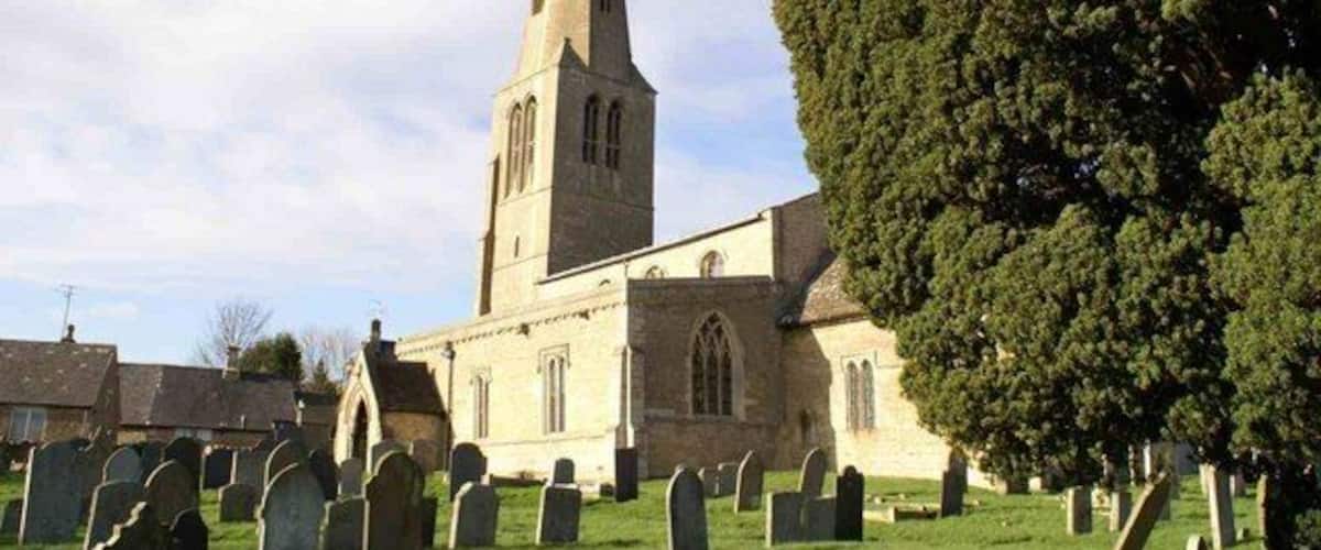 A church with a tall steeple and a graveyard in front.