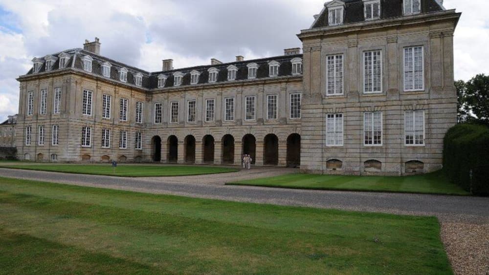 Un grand bâtiment historique en pierre, doté de nombreuses arcades et d’une façade symétrique.
