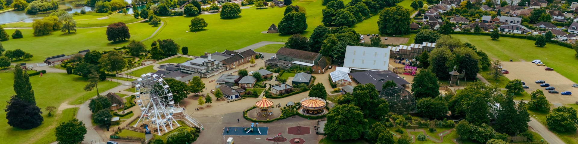 An aerial view of a park with a Ferris wheel, playgrounds, and a large building.