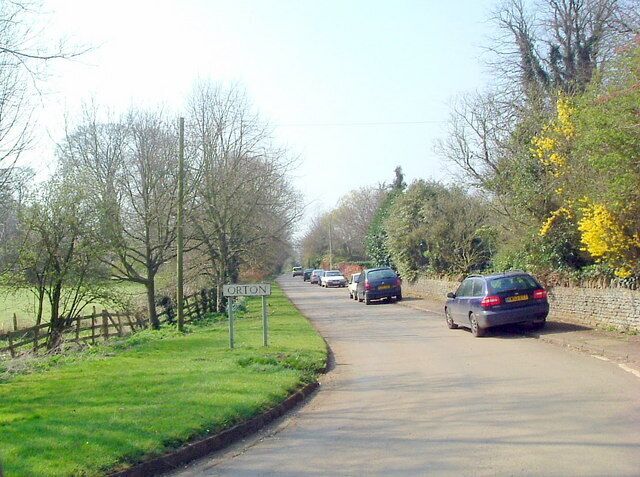A rural road with a 'ORTON' sign, surrounded by trees and grass.