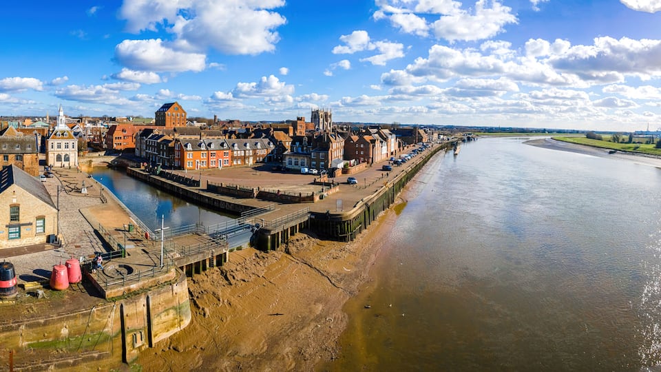 A riverside town with historic buildings, a bridge, and a church.