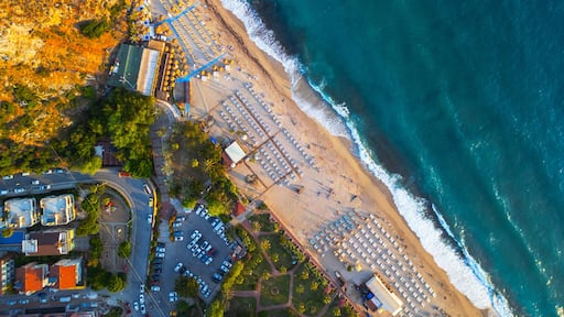 An aerial view of a coastal area with a beach, parking lots, and adjacent buildings.