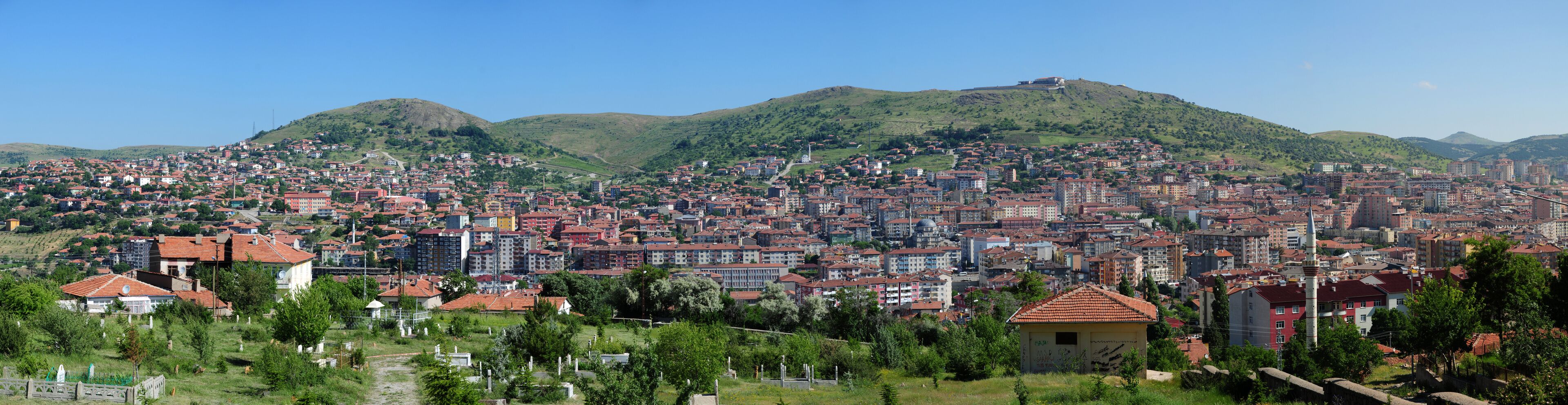 A cityscape with a prominent hill in the background and a mosque with a minaret in the foreground.
