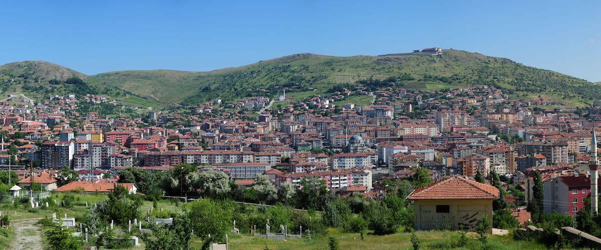 A cityscape with a prominent hill in the background and a mosque with a minaret in the foreground.