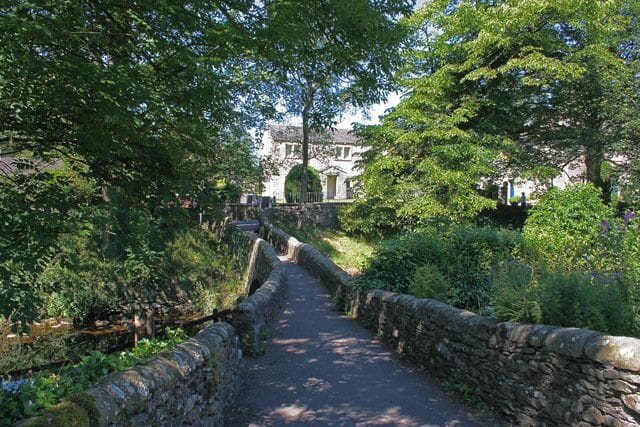 A stone pathway leading to a building surrounded by lush greenery.